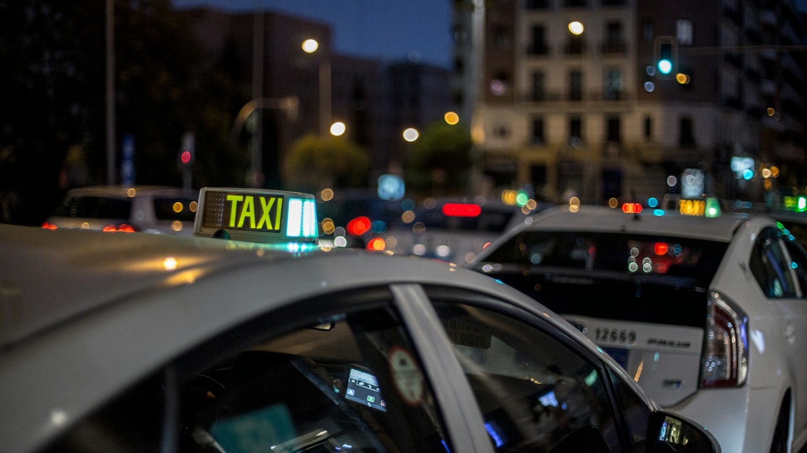 Fila di taxi bianchi in attesa di notte con l'insegna del taxi accesa