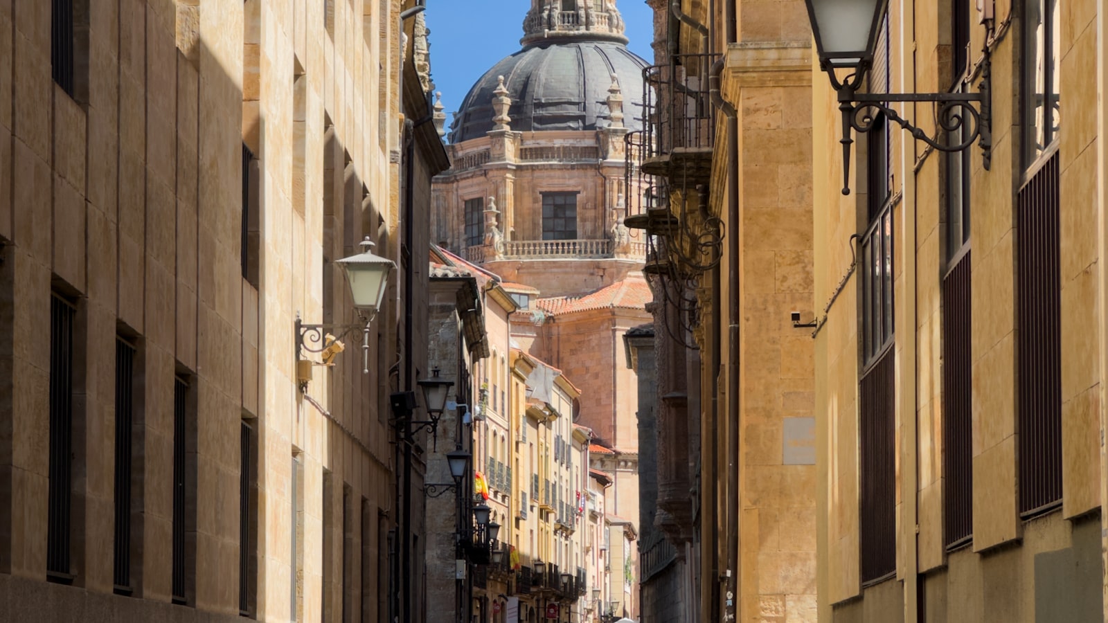 Une rue du centre historique de Salamanque avec le dôme de La Clerecía en arrière-plan